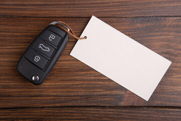 Car insurance or rent concept. Vehicle security key with blank tag on the wooden background - 515110119