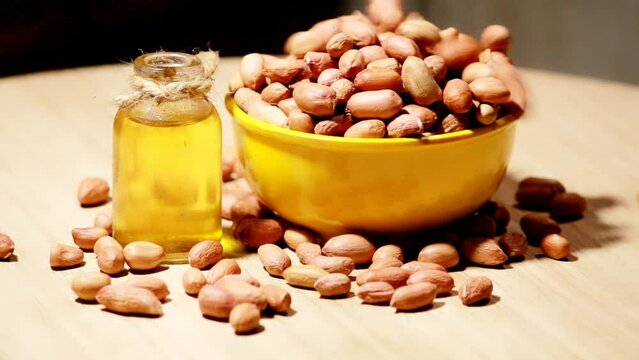 Whole peanut and peanut oil on table, eatable groundnut oil,peanuts in wooden bowl with canola oil,selective focus