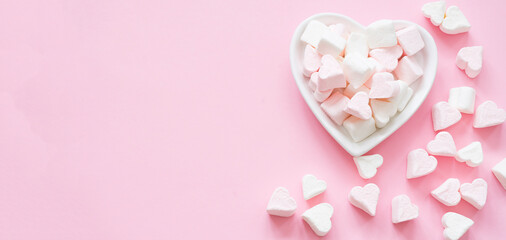 Heart-shaped marshmallows on a pink background