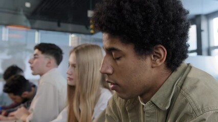 Close-up diverse group people sitting in row students classmates sitts in classroom at lesson listening to lecture writing exam writes down notes studying in college teamwork higher education concept