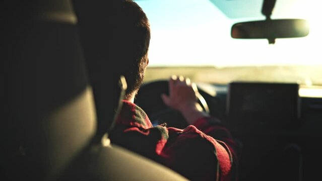 Rear view in saloon auto on male who driving on rural road. Blurred view from front window car and rear view inside mirror. Summer travel by transport outside city on uneven sections bumps and pits.