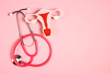 Women's health awareness concept. Uterus symbol with stethoscope on pink background. Diagnostic and research women's reproductive system.