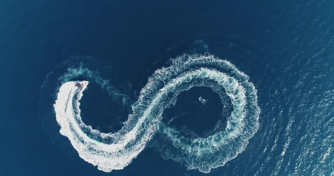Aerial top view of a white pleasure boat on a summer day. Powerboat turn loop eight on the sea making metaverse infinity future concept. 