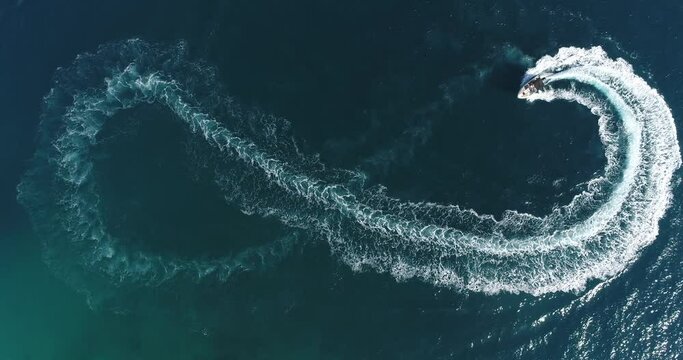 Aerial top view of a white pleasure boat on a summer day. Powerboat turn loop eight on the sea making metaverse infinity future concept. 