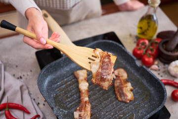 Bacon Being Cooked in grill frying pan Skillet at domestic kitchen