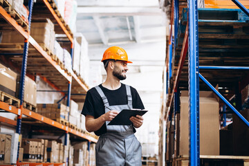 Workman writing on clipboard paper checking the goods at the factory