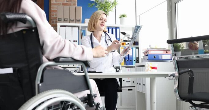 Professional doctor consults patient in wheelchair checks x-ray
