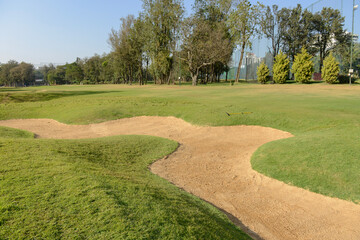 A sand bunker in a golf course on a clear day