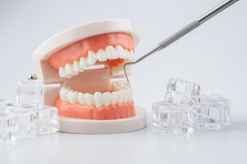 Tooth model with ice cubes and dental scaling tools, the concept of treating sensitive teeth