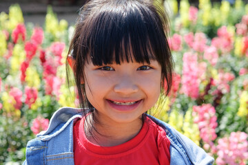 Asian child girl is smiling bright and cute on colorful flower background