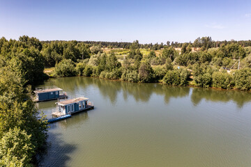 Fototapeta na wymiar a panoramic view of the green forest and the lake and the glampings standing on the shore on a sunny summer day taken from a drone