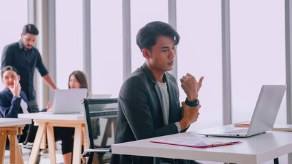 A young company employee is feeling tired while sitting at work for a long time.