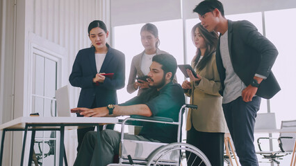 A disabled company employee is explaining a computer program to a group of colleagues.