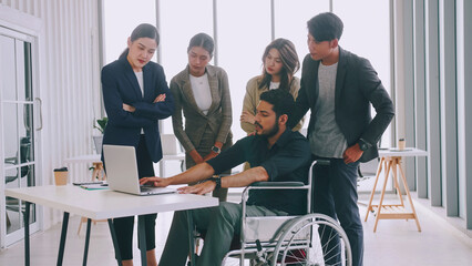 A disabled company employee is explaining a computer program to a group of colleagues.