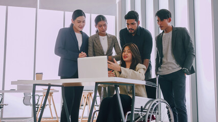 A disabled company employee is explaining a computer program to a group of colleagues.