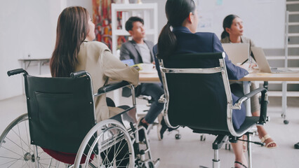 A disabled company employee is able to work happily with colleagues in the office. A group of marketers are having a discussion at the meeting.