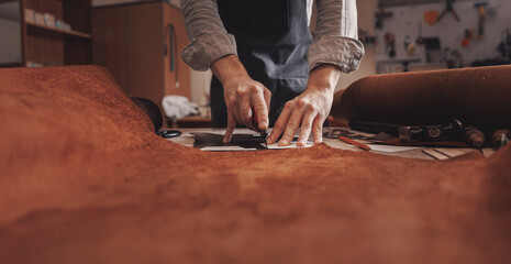 Tailor cobbler hold different rolls natural brown leather, working with textile in workshop