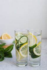 Two long glasses of infused cucumber water with lemon and mint. Hard light. copyspace