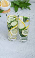 Two long glasses of infused cucumber water with lemon and mint. Hard light. copyspace