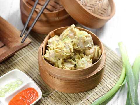 Siomay ayam, steamed dumpling dimsum with the main ingredients of chicken and shrimp. Served in traditional bamboo steamer on white background