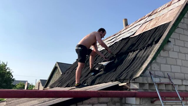 roofer without protective clothing working on the roof. Replacing slate or other roofing materials. The concept of working on your summer cottage
