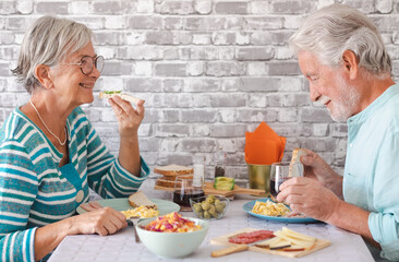 Smiling senior couple sitting face to face at home table enjoying brunch or breakfast together at...