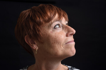 portriat of a middle-aged woman looking up on black background