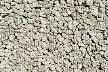 Stone wall in wire frame. Textured background of a stone wall with iron netting.