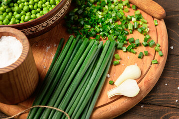 green sweet peas on a dark wooden background, onion, salt, still life, concept of fresh and healthy food