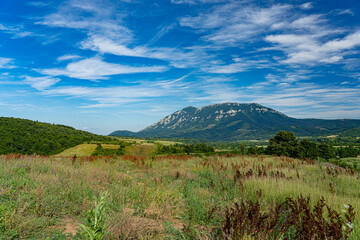 Fototapeta premium Panoramic view of a valley with a mountain on the horizon under a blue cloudy sky