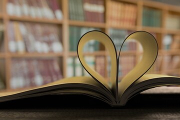 An open book forming a heart with two pages in the center, in the library. In the background are...