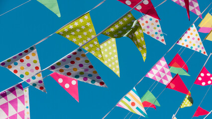 Obraz premium Banderines triangulares de fiesta de colores sobre cielo azul