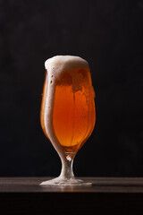 Tulip glass of beer on black background.