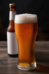 Bottle and glass of beer on black background.
