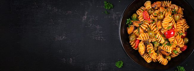 Classic italian pasta fusilli marinara with mussels, green olives and capers on dark table.  Fusilli pasta with sauce marinara. Top view, banner