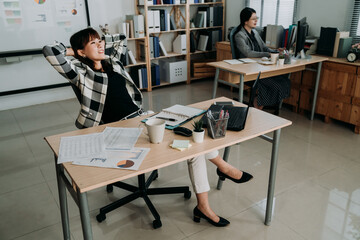 happy asian business woman is looking into distance crossing legs with smile and keeping hands...