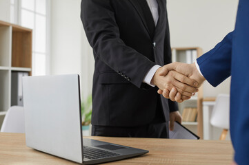 Handshake after successful business meeting in office. Close up of businessman shakes hands with male client after successful approval of business agreement. Concept of business relations.