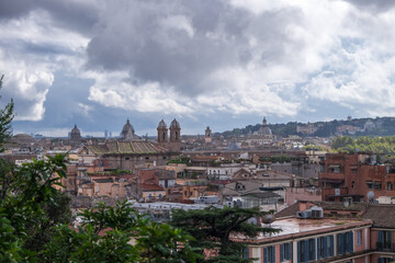 Fototapeta na wymiar Roofs of Rome with cupolas of ancient churches in the distance. Shot on a rainy day with stormy clouds 