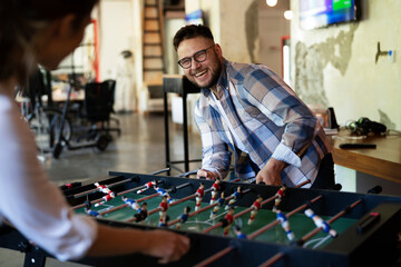 Colleagues having fun at work. Businessman and businesswoman playing table soccer