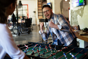 Colleagues having fun at work. Businessman and businesswoman playing table soccer