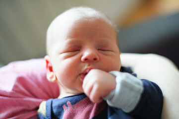 Close-up detail portrait of mother holding cute little peaceful newborn baby in her hands. Beautiful child calm sleeps soundly