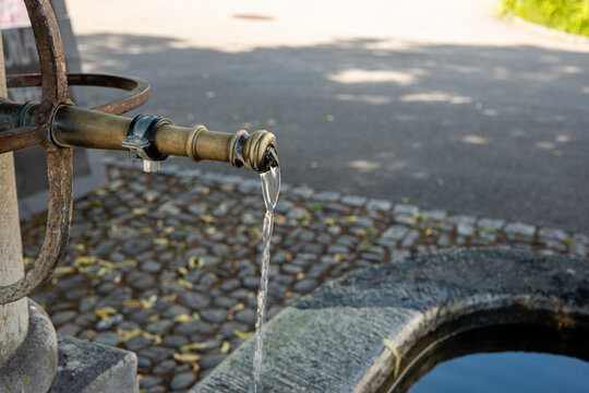 Old Vintage Stone And Forged Steel Public Drinking Water Fountain In A Small Village In Switzerland, Europe. Clear Pouring Water From The Faucet, Close Up Shot, No People