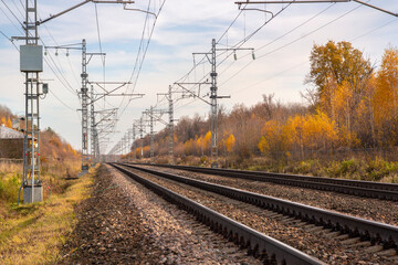 Railroad with power supply pytons in autumn season. Travel landscape