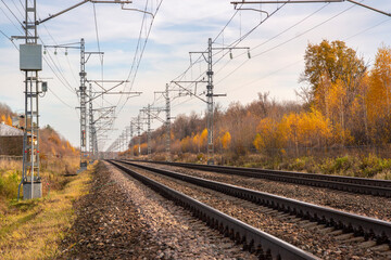 Fototapeta premium Railroad with power supply pytons in autumn season. Travel landscape