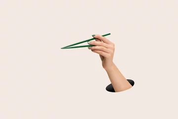 Foto op Canvas Female hand holding green chopsticks on clean pink background © Ladev