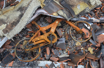 Rusty frame of a childrens bicycle in the courtyard of a private destroyed house after the occupation of the Kyiv region by the Russian army.