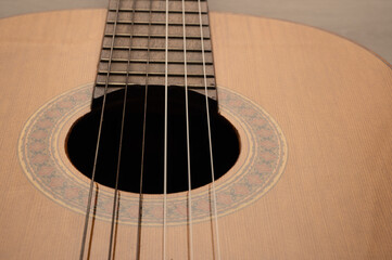 Classical guitar body on a light wood background. Close up, with the sound hole offset to allow...