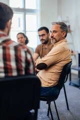 A focused man attends group therapy, being calm and listening to others.