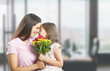 Fototapeta na wymiar Smiling mother hugging little daughter at weekend celebration Happy Mothers Day holding blooming bouquet of tulips