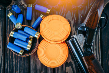 Shooting sports equipment for trap shooting on wooden table. Air-gun and bullets.